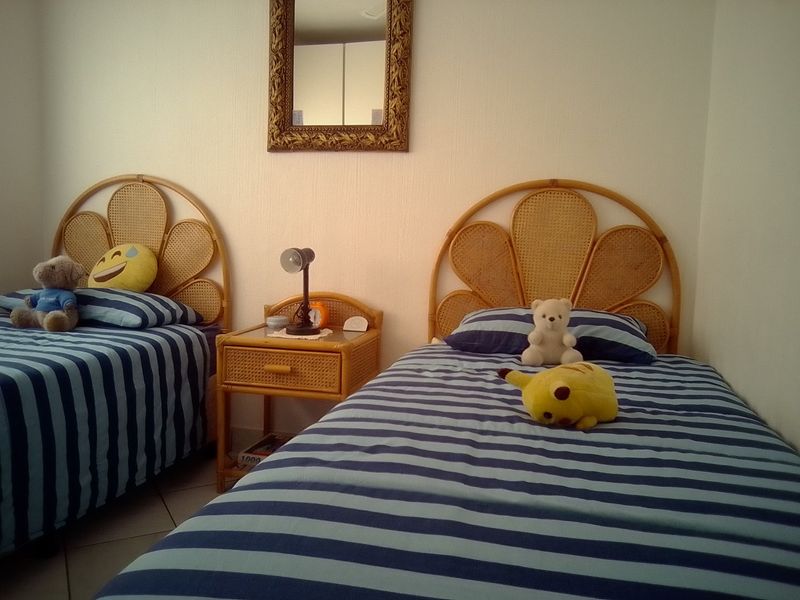 A bedroom featuring tiled flooring and neutral wall finishes, currently configured with twin beds.