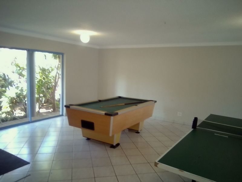 Spacious living area featuring neutral tiled flooring and large sliding glass doors providing natural light and garden access.