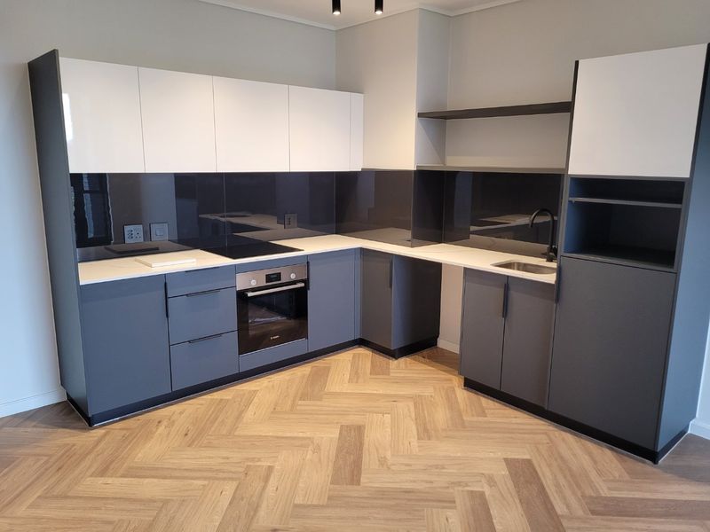 Modern kitchen featuring sleek two-tone cabinetry, integrated appliances, glass splashback, and high-quality herringbone wood flooring in a clean, contemporary design.