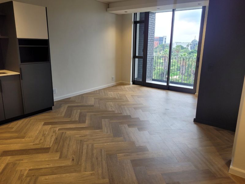 Modern open-plan living area featuring high-quality herringbone wood flooring, sleek built-in cabinetry, and large sliding doors leading to a balcony with scenic views.