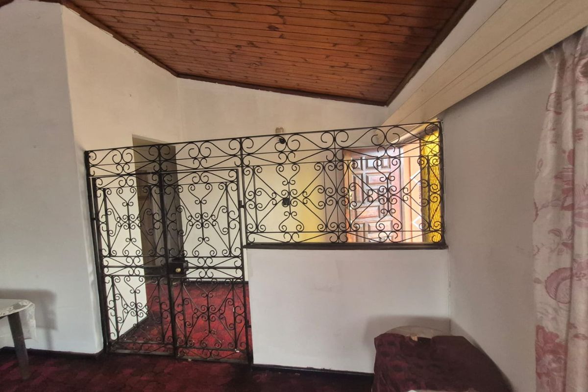 Living area featuring a timber-clad ceiling and a decorative wrought iron security partition separating the space from the entrance.