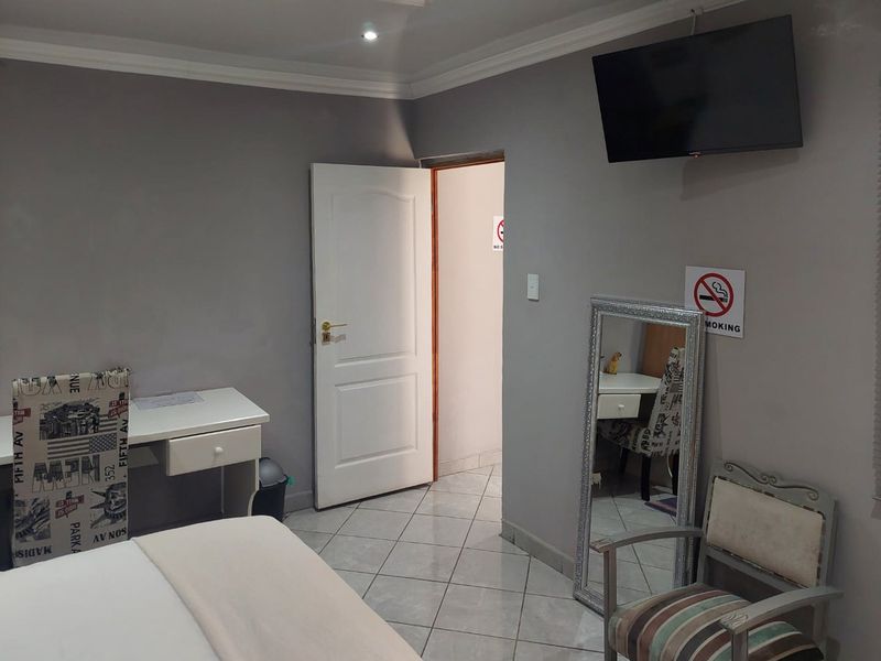 A bedroom featuring tiled flooring, coved ceilings, and recessed lighting, providing a functional space with direct access to an adjoining room.