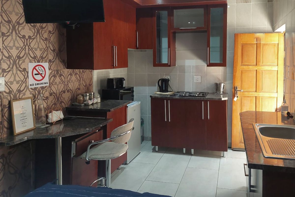 Compact kitchen featuring dark wood cabinetry, granite countertops, a gas hob, and tiled finishes, providing a functional space for meal preparation.