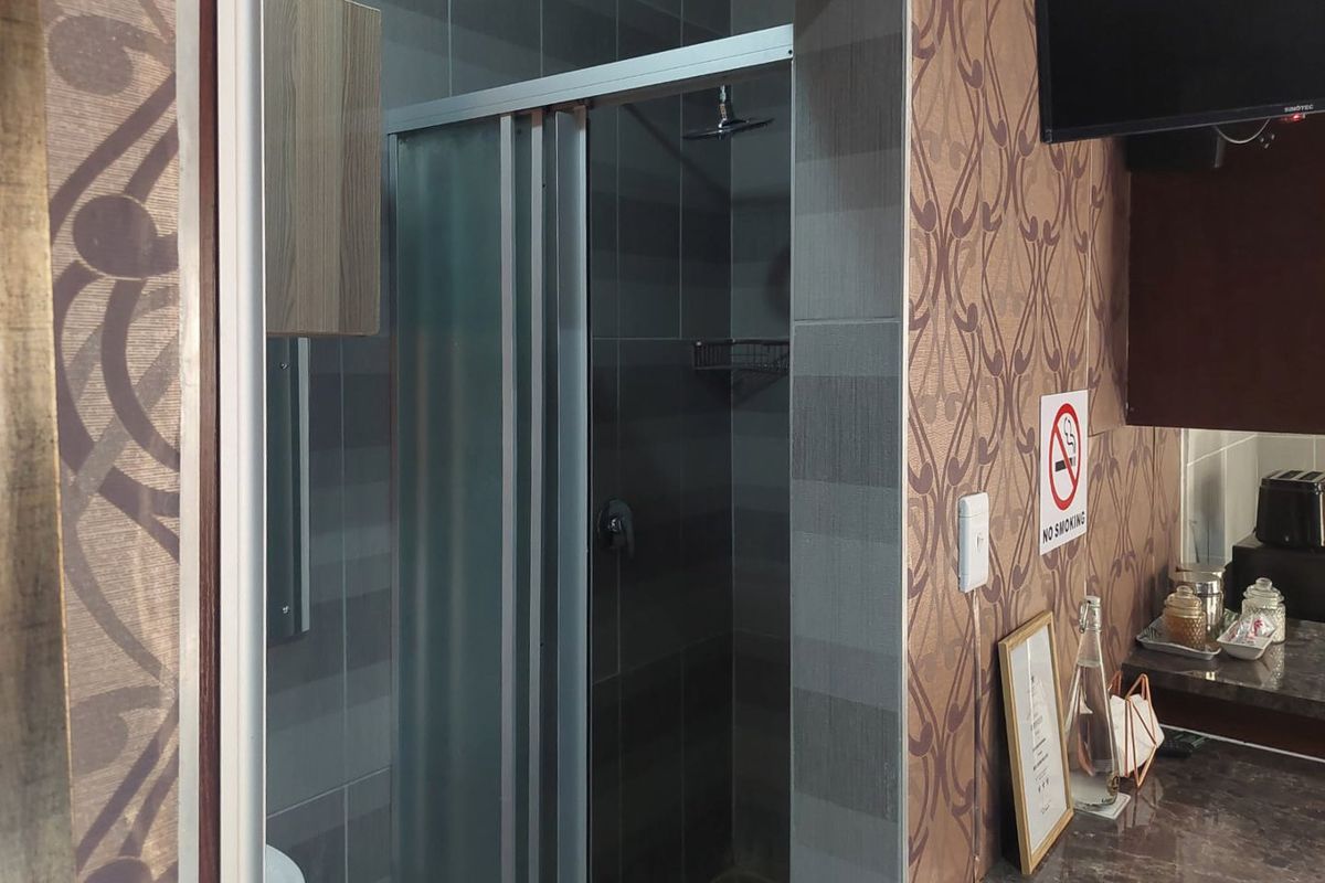 A compact bathroom featuring a tiled shower enclosure with a modern shower head and built-in shelving, integrated into the apartment layout.