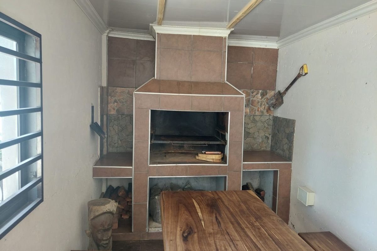 Covered patio area featuring a large built-in tiled braai with integrated storage and recessed ceiling lighting.