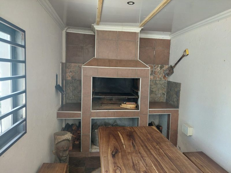 Covered patio area featuring a large built-in tiled braai with integrated storage and recessed ceiling lighting.
