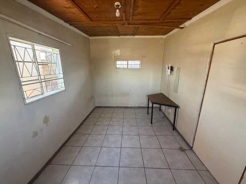 A vacant bedroom featuring tiled flooring and a timber ceiling, requiring cosmetic updates and wall repairs to improve its overall condition.