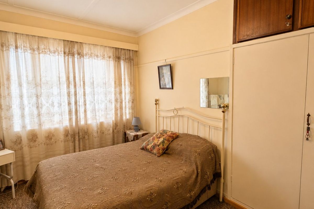 A cozy bedroom featuring a built-in wardrobe with overhead storage, coved ceilings, and a classic picture rail detail.