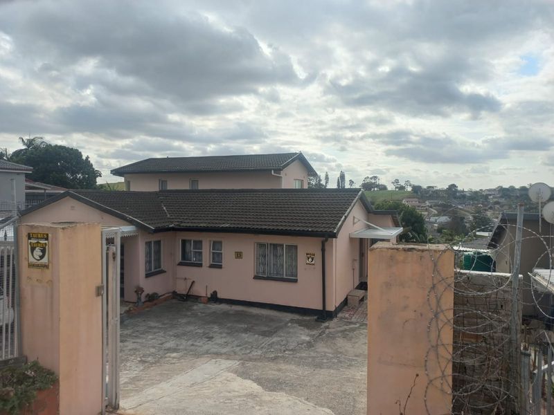 Front exterior view of a single-story residential house featuring a concrete driveway, tiled roof, and secure boundary wall with razor wire.