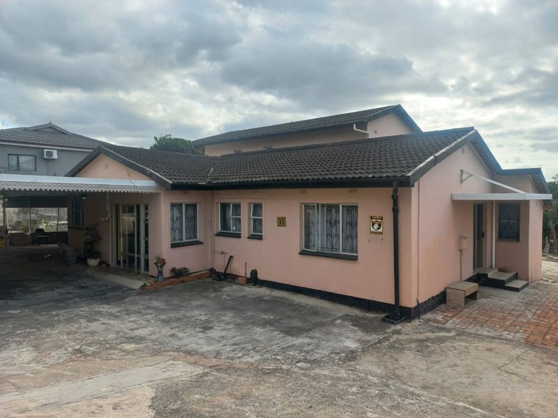 Front elevation of a single-story residential property featuring a tiled roof, security bars on windows, and a paved driveway with an attached carport.