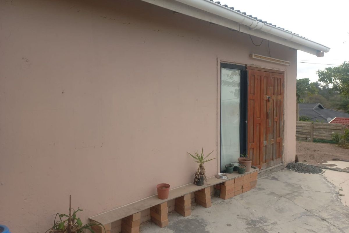 Rear exterior view of the house featuring a concrete patio area, timber door, and guttering system.