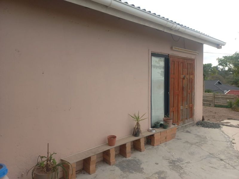 Rear exterior view of the house featuring a concrete patio area, timber door, and guttering system.