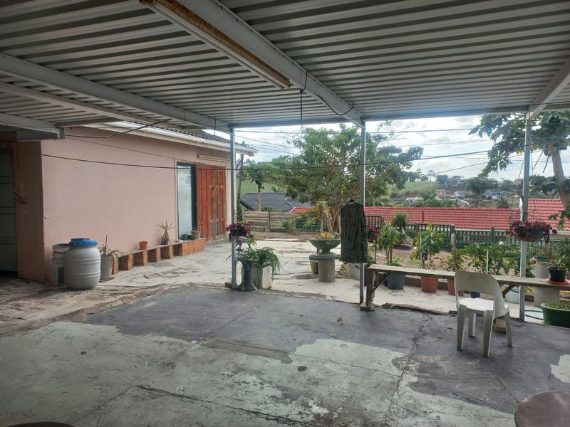 A covered outdoor patio area featuring a corrugated metal roof and concrete flooring, offering potential for renovation into an inviting entertainment space.