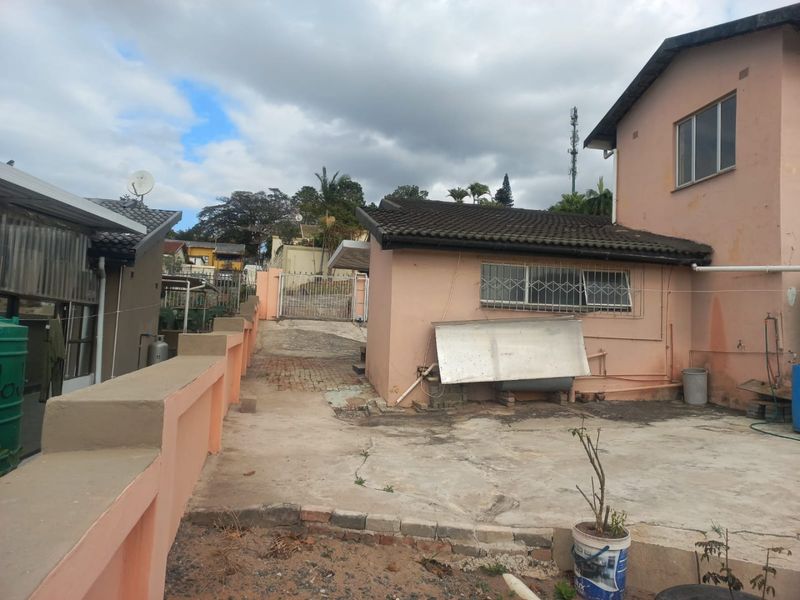 Rear exterior view of the property featuring a concrete driveway, security gate, and a solar water heater mounted on the exterior wall.