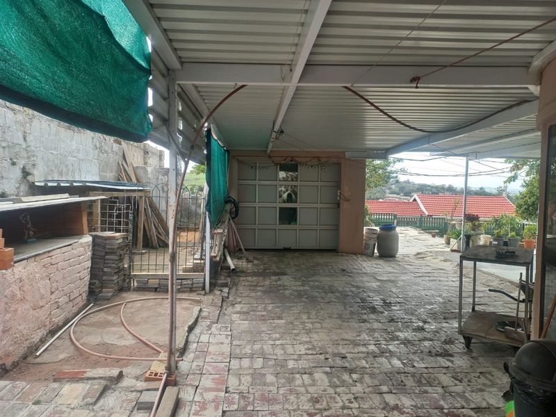 A covered outdoor patio area featuring brick paving, a metal roof structure, and direct access to a garage.