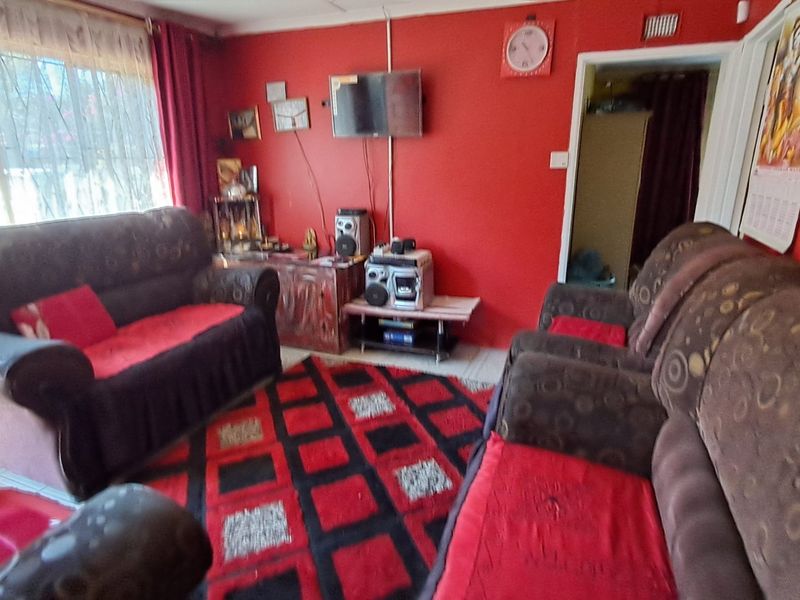 A living room featuring tiled flooring and coving, currently decorated with bold red wall paint.