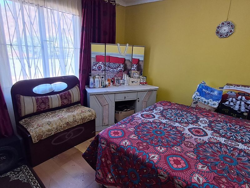A bedroom featuring a window with a security gate and yellow painted walls.