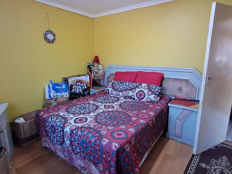 A bedroom featuring laminate flooring and a built-in headboard, requiring cosmetic updates to improve its overall appeal.