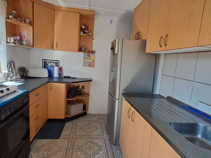 A functional kitchen featuring laminate cabinetry, tiled backsplash, and patterned floor tiles, offering a dated aesthetic ready for modernization.
