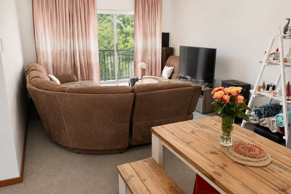 A living room area featuring carpet flooring and a sliding glass door providing access to a balcony.