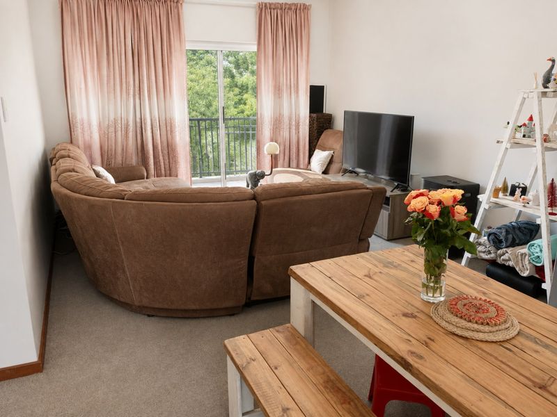 A living room area featuring carpet flooring and a sliding glass door providing access to a balcony.