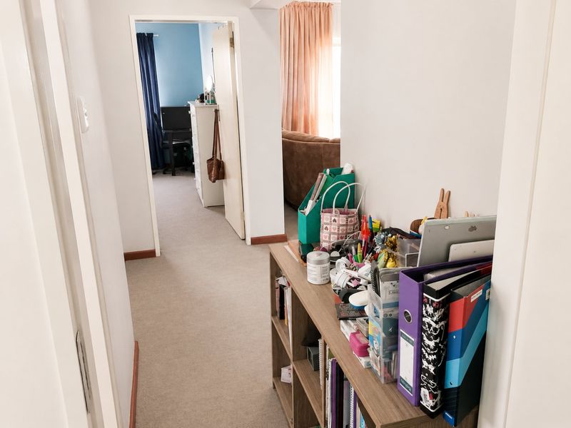 A functional hallway connecting multiple rooms, featuring neutral wall finishes and carpeted flooring throughout.