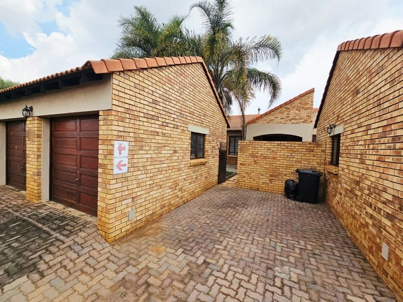 Exterior view of a townhouse featuring face brick construction, a tiled roof, and a paved driveway leading to a garage.