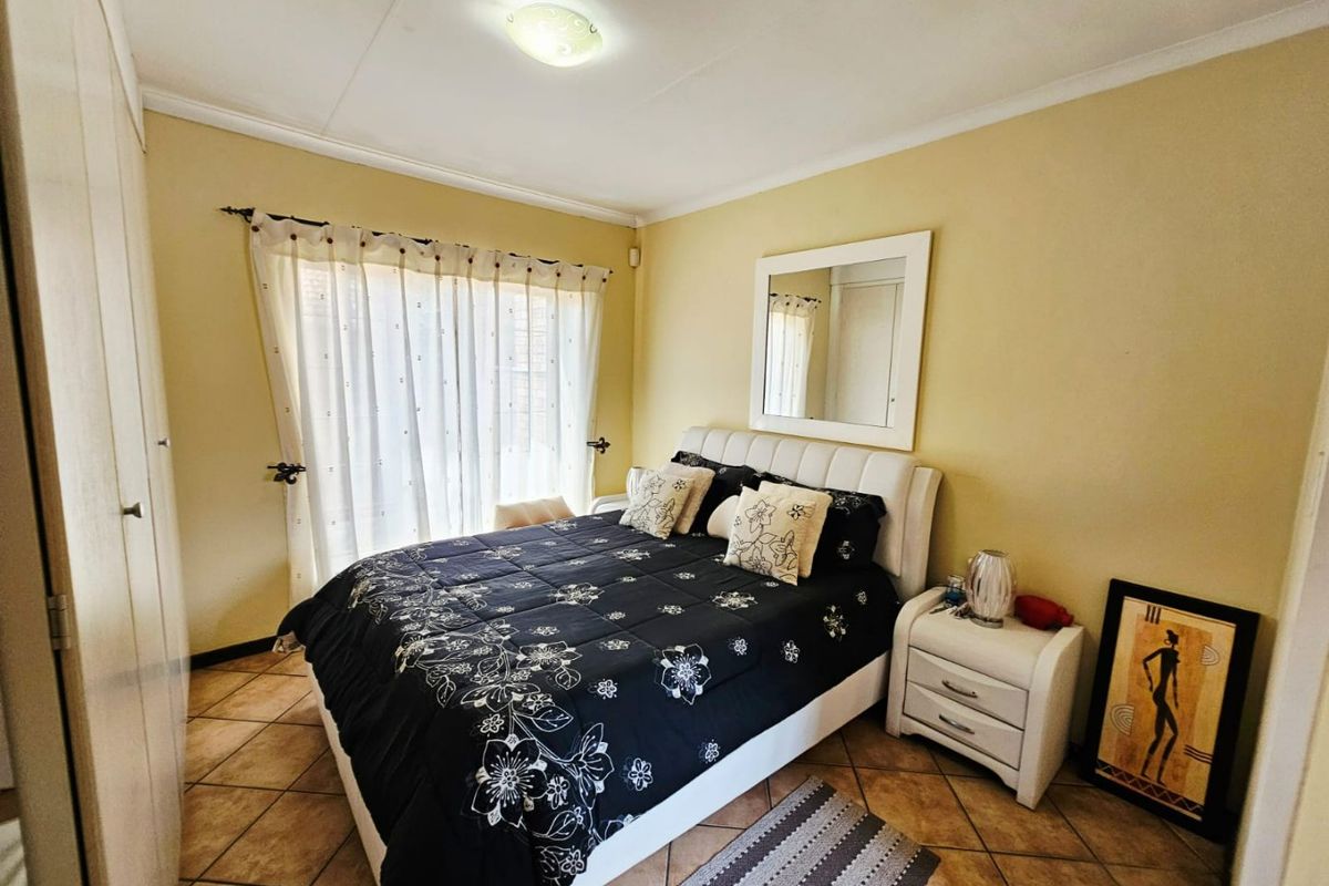 A functional bedroom featuring tiled flooring, built-in cupboards, and a ceiling light fixture, providing a comfortable and practical living space.