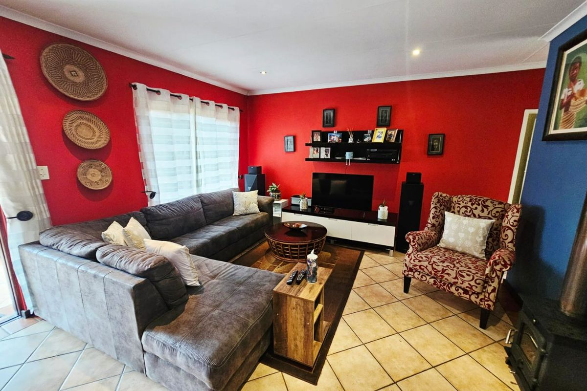 A living room featuring tiled flooring, recessed downlighting, and a built-in wood burning stove, finished with bold red accent walls.