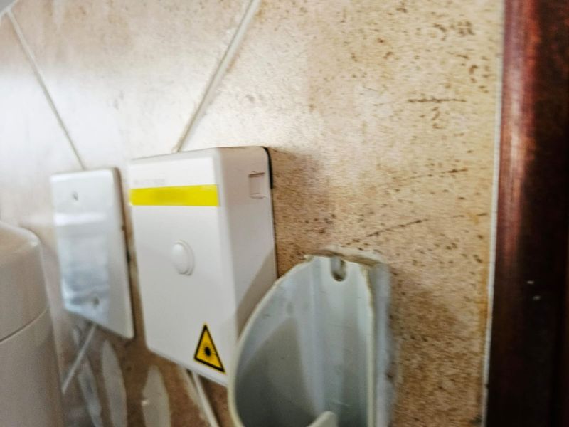 Close-up view of wall-mounted electrical switches and utility fixtures on tiled wall surfaces showing signs of wear.