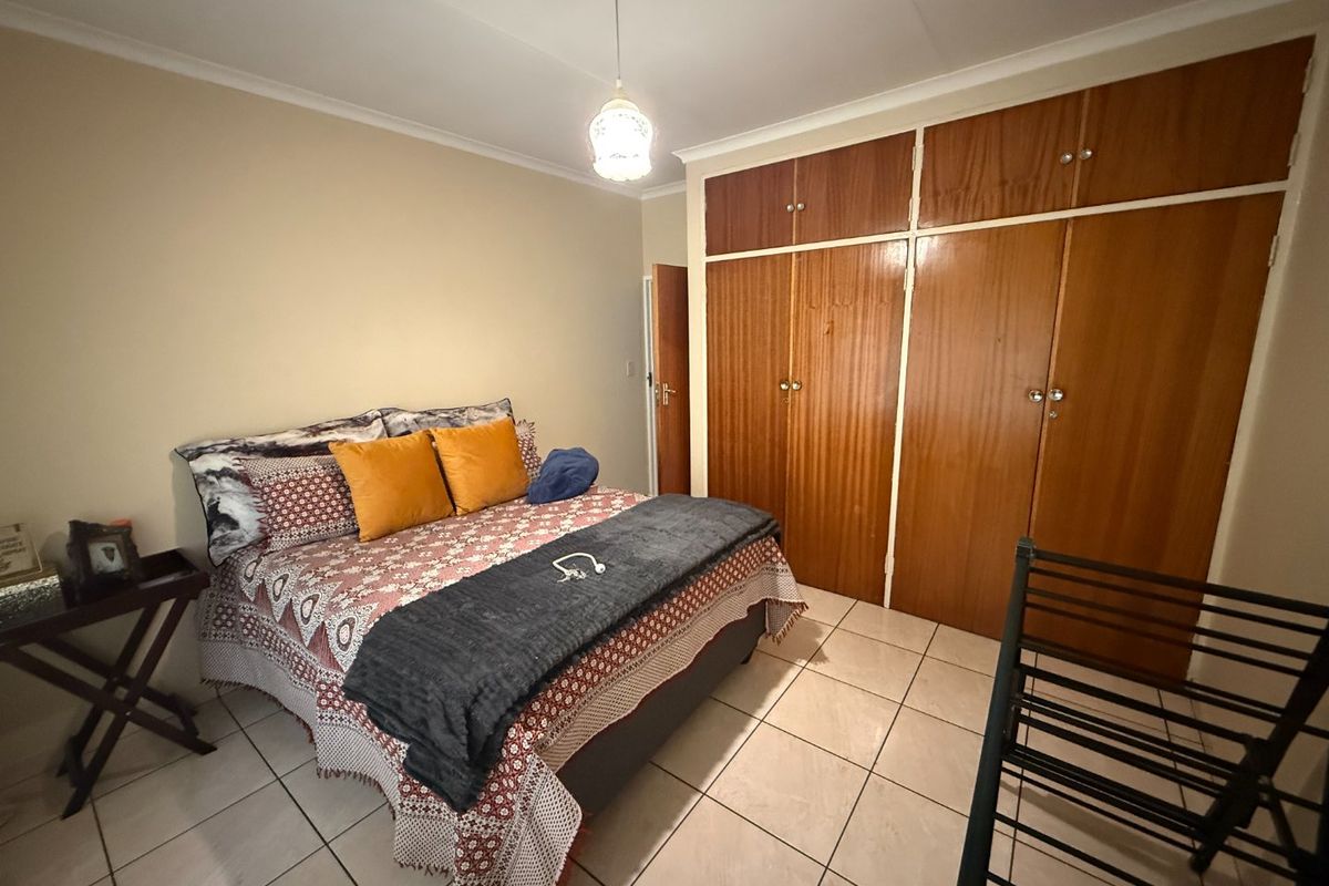 A bedroom featuring tiled flooring and built-in wooden cupboards providing ample storage space.