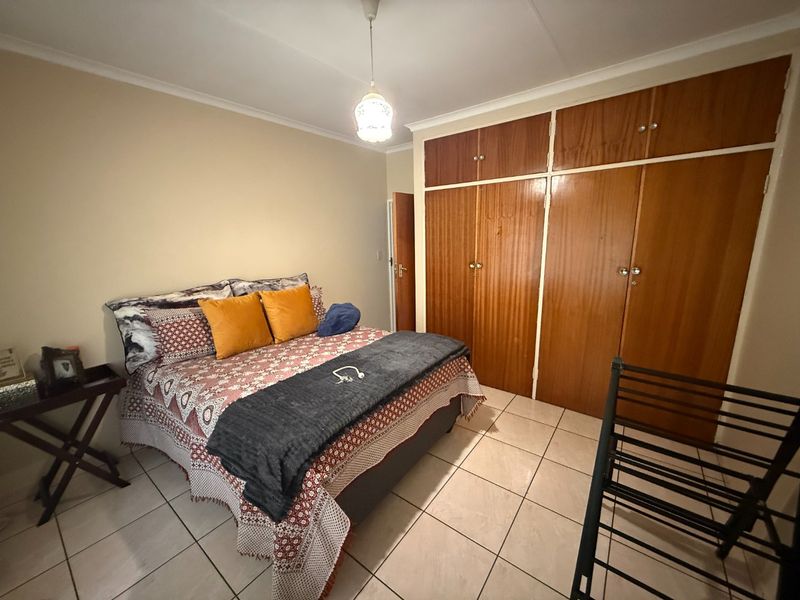 A bedroom featuring tiled flooring and built-in wooden cupboards providing ample storage space.