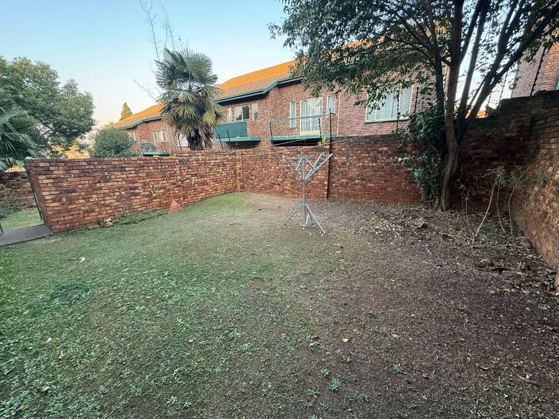 A private rear garden area featuring a brick boundary wall and established lawn, offering potential for landscaping and outdoor improvement.