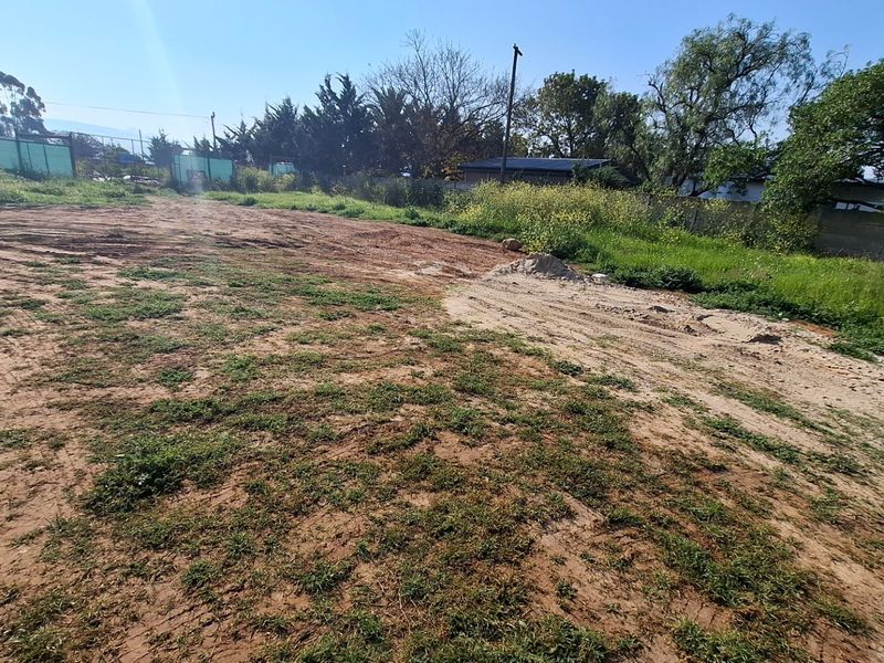 A vacant residential plot featuring natural terrain, perimeter fencing, and boundary walls, offering a blank canvas for future development.