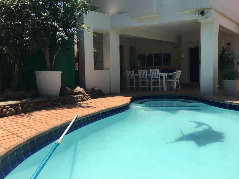 Outdoor pool area featuring a tiled surround and a covered patio space, ideal for relaxation and entertaining.