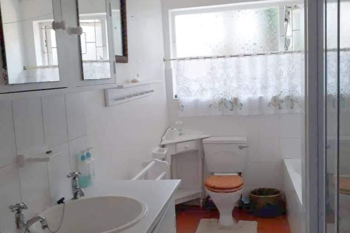 A functional bathroom featuring a vanity cabinet, basin, toilet, bathtub, and a separate shower enclosure with tiled flooring.
