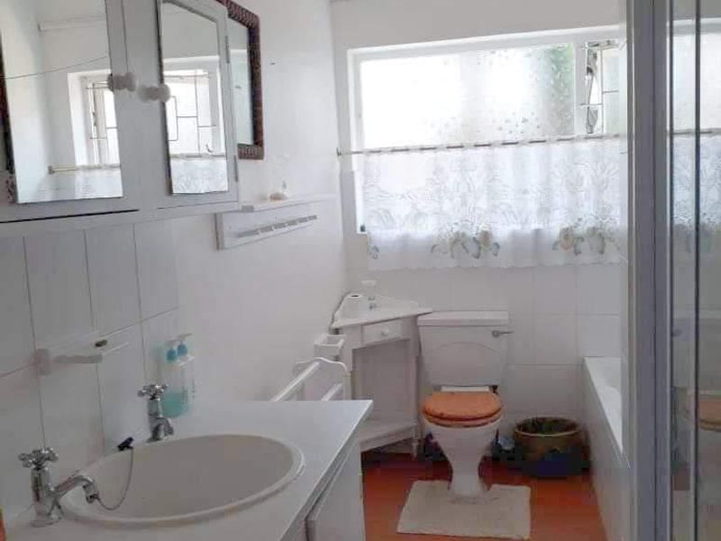 A functional bathroom featuring a vanity cabinet, basin, toilet, bathtub, and a separate shower enclosure with tiled flooring.