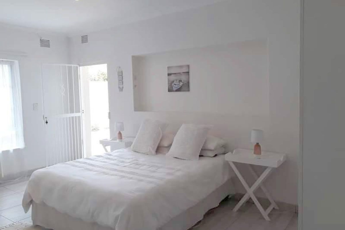 A bright bedroom featuring a recessed wall niche, tiled flooring, and direct access to an outdoor area through a security gate.