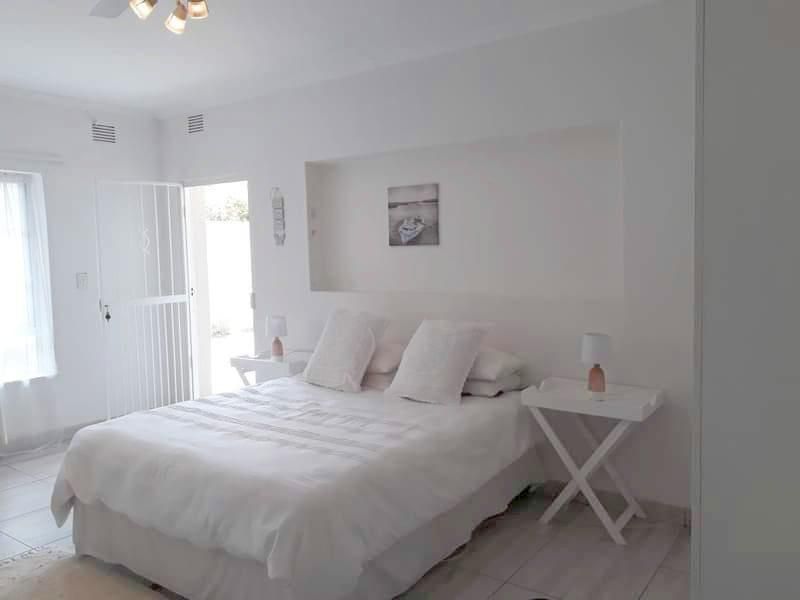 A bright bedroom featuring a recessed wall niche, tiled flooring, and direct access to an outdoor area through a security gate.