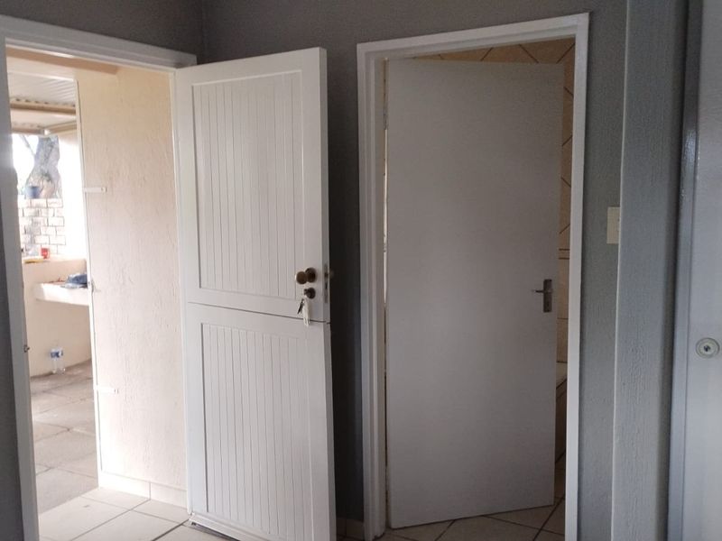 A functional hallway area featuring tiled flooring and multiple internal doors providing access to adjacent rooms.