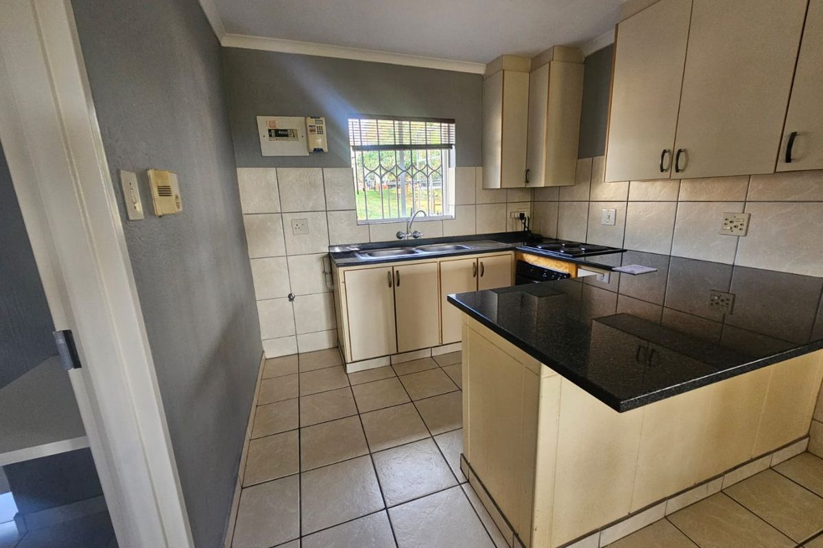 A functional kitchen featuring granite countertops, built-in cabinetry, a double basin sink, and ceramic tile flooring, offering a clean and practical workspace.