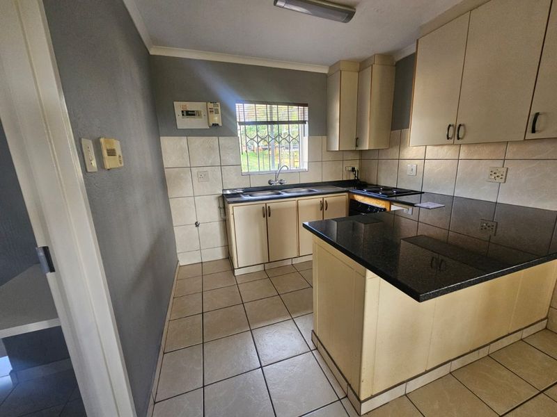 A functional kitchen featuring granite countertops, built-in cabinetry, a double basin sink, and ceramic tile flooring, offering a clean and practical workspace.