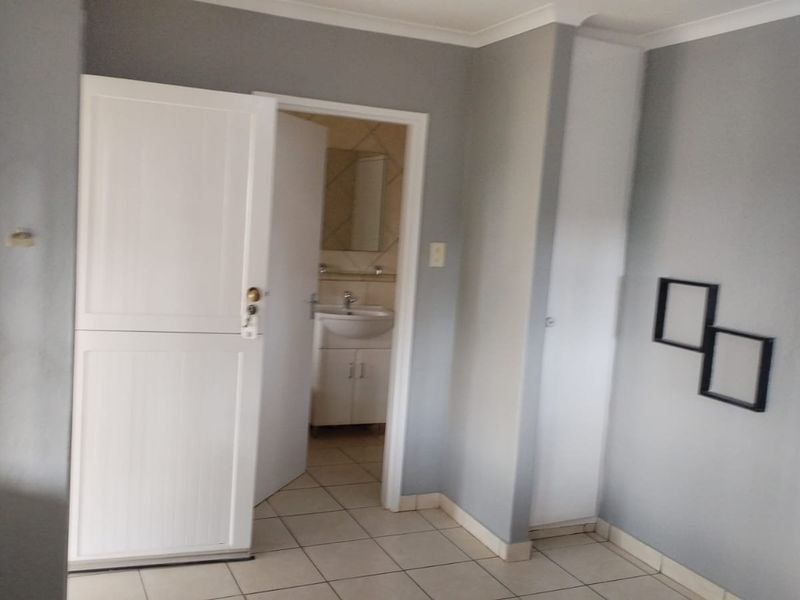 A bedroom featuring tiled flooring and an en-suite bathroom with a built-in vanity and sink.