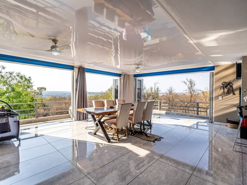 Spacious covered patio featuring a high-gloss ceiling, ceiling fans, and expansive folding glass doors that open to panoramic landscape views.