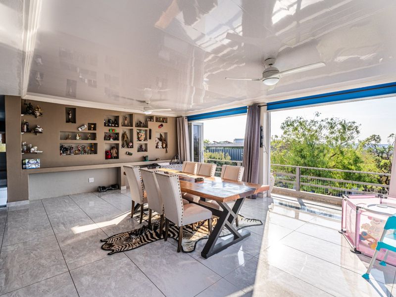 Spacious dining area featuring a high-gloss ceiling, built-in display niches, and large sliding doors opening to an outdoor balcony with scenic views.