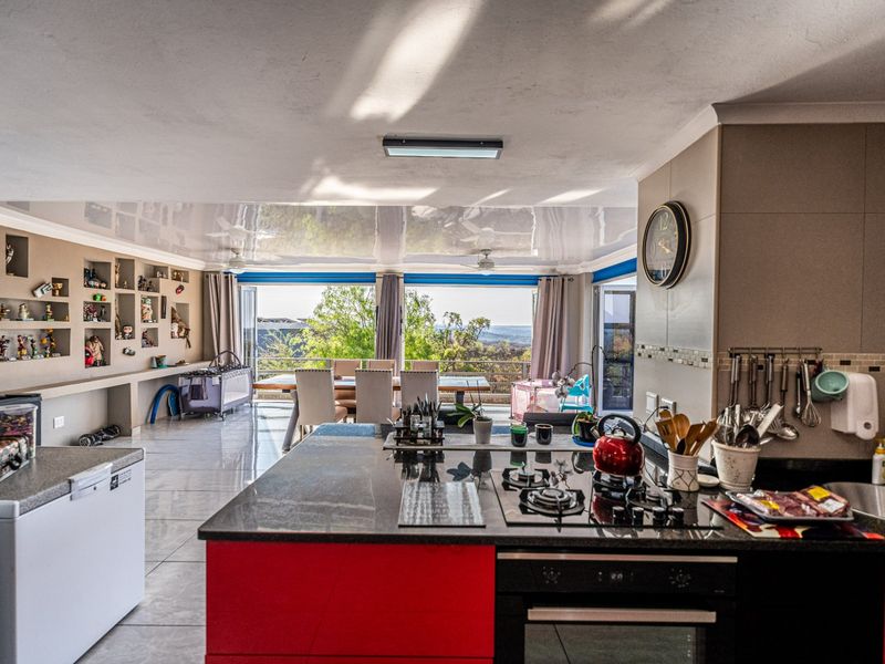 Spacious open-plan kitchen and living area featuring a central island, modern gas hob, built-in oven, and large stacking doors opening to a scenic view.