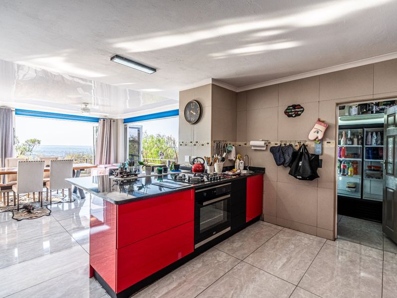 Open-plan kitchen featuring a central island with built-in oven and gas hob, granite countertops, and high-gloss cabinetry, flowing into the dining area.