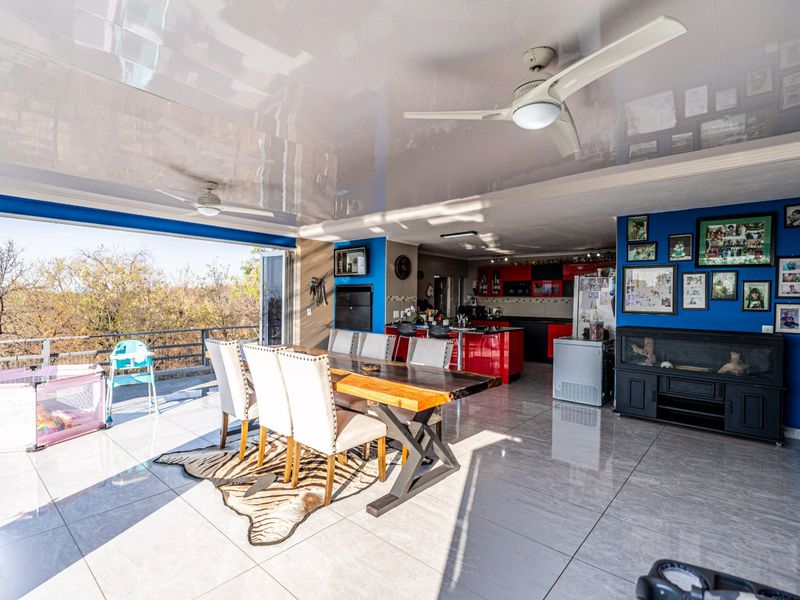 Spacious open-plan living and dining area featuring glossy ceilings, ceiling fans, large format floor tiles, and seamless access to an outdoor balcony.