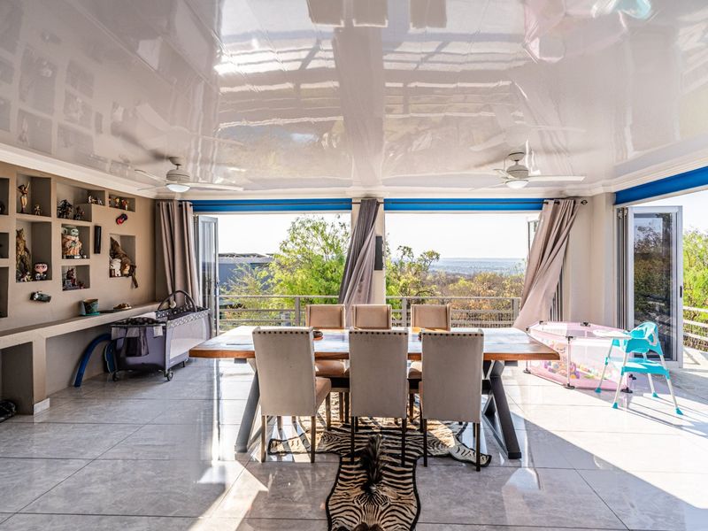 Spacious open-plan living area featuring a high-gloss ceiling, built-in shelving, and large bi-fold doors opening to an expansive outdoor view.