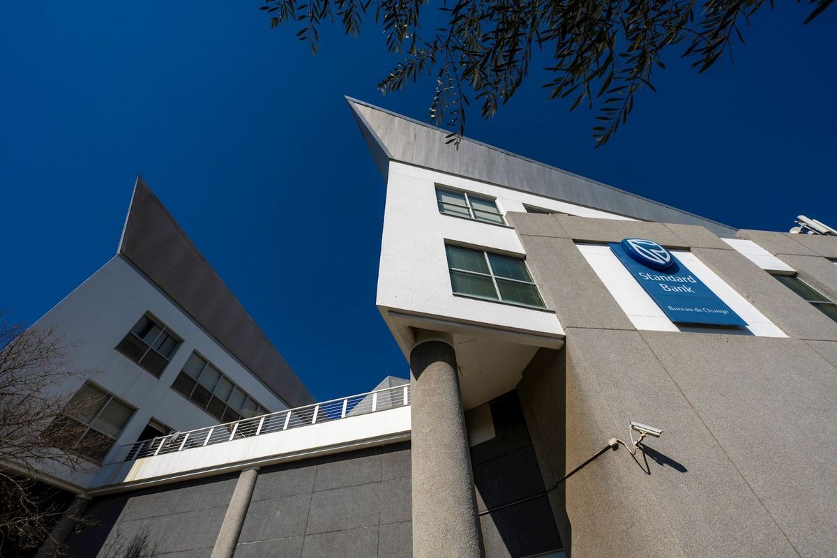 Low-angle exterior view of a modern commercial building facade featuring concrete cladding, large windows, and prominent corporate signage.